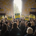 Student protesters rallying with Yes to Early Election signs in front of a large crowd and bright banners
