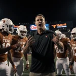 Texas Longhorns linemen practicing block with Coach Kyle Flood under stadium lights and Citrus Bowl logo at night