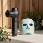 Theragun Prime rests on natural wood surface with lush greenery creating a wellness vibe