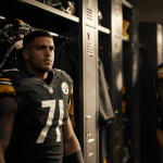 Empty locker stall revealing Steelers jersey with helmet and pads as Herbig and Sawyer stand nearby with gear scattered