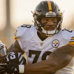 T.J. Watt tackling a teammate with helmet and pads during Steelers practice under golden light