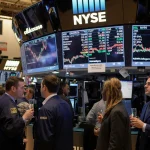 Investors gathering around a screen with champagne flutes and bright ticker in focus