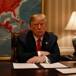 President Donald Trump sitting at wooden desk with resolutions fluttering and South American map red Venezuela and Mexico.