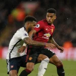 Tyler Adams struggling in tackle with Matheus Cunha tangled legs and arm outstretched stadium lights Manchester vs Bournemout