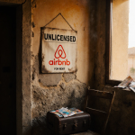 Unlicensed Airbnb sign hanging precariously on a stone wall with a vintage Spanish door and crumpled tourist brochures.