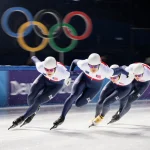 US short track speedskater racing down icy track with spotlight highlighting determined expression and Olympic rings.