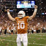 Arch Manning raises arms in victory with confetti swirling and Texas Longhorns scoreboard showing 41-27