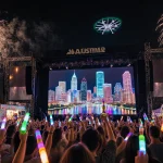 People cheering with glow sticks and champagne with fireworks and Austin skyline reflected in a screen