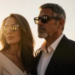 George and Amal Clooney looking at Eiffel Tower with golden light and French flags in background.
