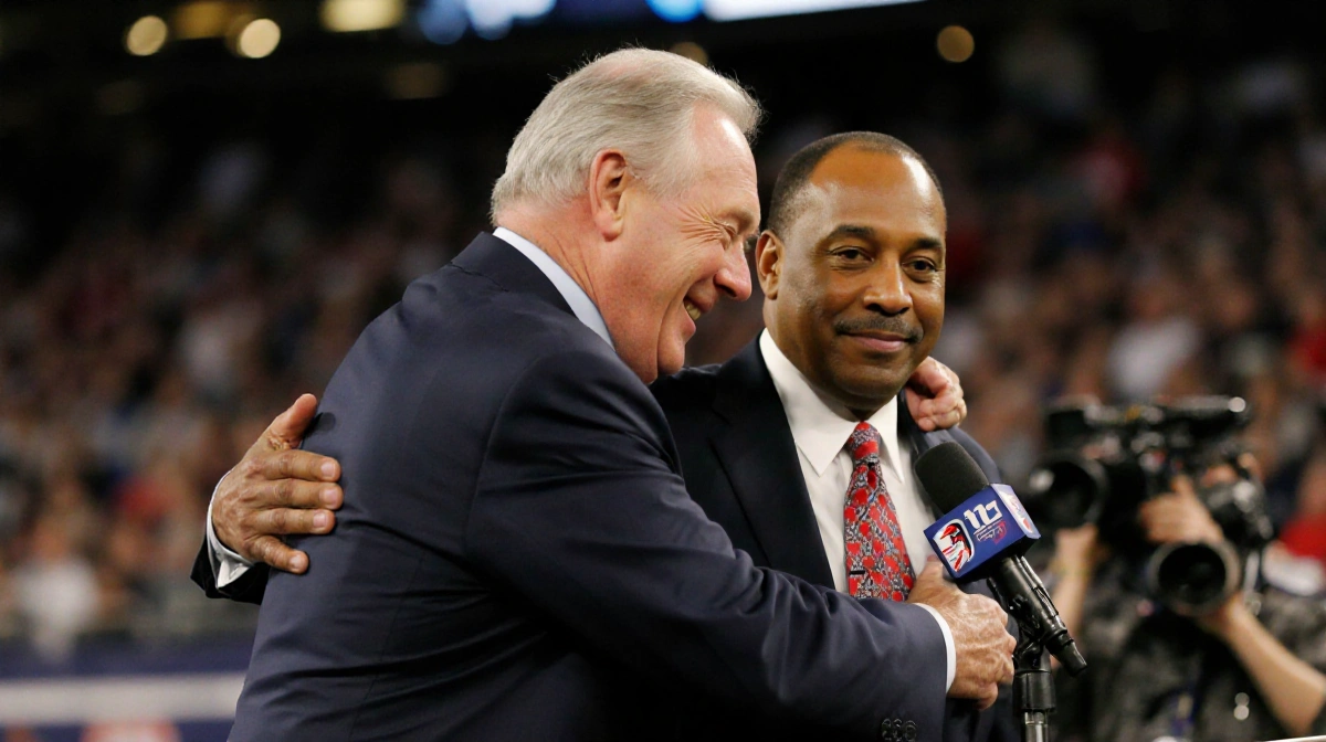 Arthur Blank embraces Arthur Smith at a post-game press with Smith speaking into a microphone over a blurred media backdrop