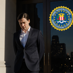 FBI agent stands looking down at feet with courthouse entrance and blurred flag hinting resignation