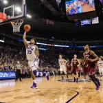A.J. Dybantsa driving toward the basketball hoop with BYU fans teammates in blue jerseys Kansas State players react red behin