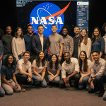 34 volunteers looking at a NASA tracking screen with warm lighting showing global cooperation