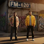 Four suspects stand with caution and resolve against a faded graffiti‑covered street sign reading FM 620 in warm sunlight.