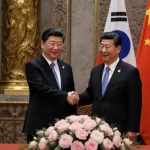 Lee Jae Myung and Xi Jinping shaking hands with peaceful peonies and cherry blossoms in front of Hall of Supreme Harmony