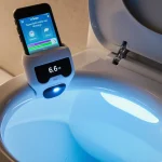 Close-up of a sleek, modern bathroom with a toilet in the center. A small, futuristic device clips onto the inside of the toi