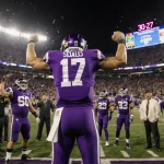Ken Seals raises arms in victory on the field with scoreboard showing 30-27 overtime win and cheering teammates