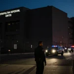 Nicolás Maduro looking back at camera with police motorcade fading into distance near Brooklyn detention center entrance