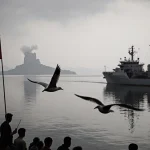 Ballistic missiles rise over a North Korean dock with a cargo ship sailing away under a grey ominous sky