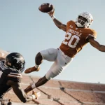 Parker Livingstone leaps over a defender snatching a pass with arms outstretched in Longhorns stadium backdrop.