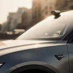 Polestar 4 parked with golden light illuminating its sleek roof and digital rearview mirror against a blurred urban backdrop