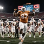 Texas Longhorns players celebrate with 387‑pound Ian Geffrard dominating center under vibrant stadium lights on football fiel