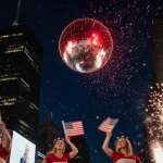 Red ball dropping over Times Square with fireworks and confetti lighting night sky