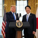 President Trump and Prime Minister Kishida shaking hands with flags behind them and Tokyo Tower visible during diplomacy