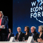 President Trump standing confidently at podium with World Economic Forum logo on screen and diplomats watching skeptically