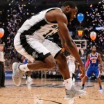 Victor Wembanyama jumps in a Spurs #12 jersey with his knee hyperextended and confetti raining over a blurred basketball cour