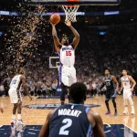 Philadelphia 76ers guard VJ Edgecombe releasing a three‑point shot with the ball arcing toward the hoop and confetti explodin