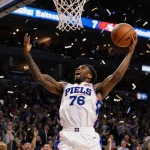 VJ Edgecombe jumps with arms raised after a buzzer‑beater with confetti and cheering 76ers crowd in the background