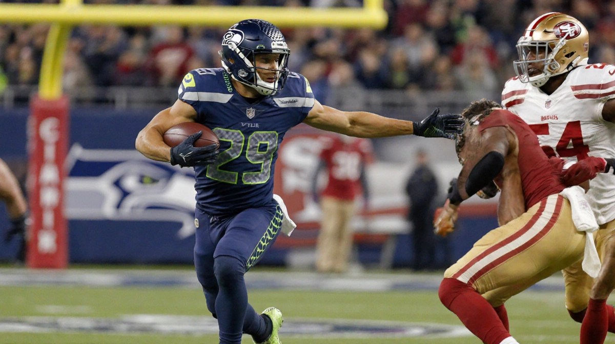 Zach Charbonnet sprinting for a touchdown with the ball and arms outstretched while the Seahawks logo glows on the goalpost.
